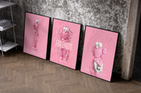 Pink Cotton Candy KAWS Friends Trio as black-framed prints leaning against a raw-plaster wall