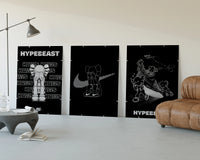 KAWS Hypebeast Poster Set three-panel set displayed beside a brown leather sofa