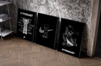 KAWS Hypebeast Poster Set set of three black-framed prints leaning against a raw-plaster wall