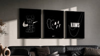 KAWS Nike Poster Set triptych in three black frames on a grey wall above a leather sofa
