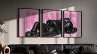 KAWS Pink Reclining Companion Set of 3 in black frames on a grey wall above a leather sofa