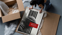 figure in helmet obscured by stripes framed print being unpacked from protective bubble wrap and a box