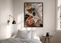 Iced Coffee with Sunglasses and Handbag print in a black frame above a bed with striped linens