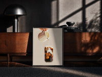 Black-framed Iced Latte Cream Pour print on the floor in front of a dark wooden console
