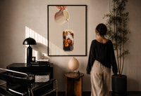 Iced Latte Cream Pour print in a black frame on a sunlit plaster wall, a woman looking on beside a mushroom lamp