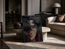 Anime ninja with red Sharingan eye print in a black frame leaning on a travertine table in a sunlit lounge