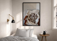 It's a Beautiful Day to Be Black print in a black frame above a bed with striped linens