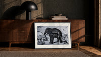 Large elephant with tusks print in a black frame leaning against a walnut console in lamplight