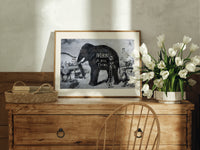 Large elephant with tusks print in an oak frame on a farmhouse dresser beside white tulips