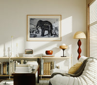 Large elephant with tusks print in an oak frame above a mid-century book console with a vintage radio