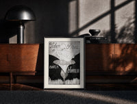 Black-framed Baby cherub sitting on flower print on a moody console with designer coffee-table books