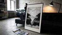 Baby cherub sitting on flower print in a slim black frame leaning on a dark sofa in a concrete print studio