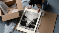 Baby cherub sitting on flower framed print being unpacked from protective bubble wrap and a box