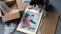 Woman holding soap box framed print being unpacked from protective bubble wrap and a box