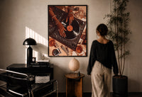 Jeweled Hands on a Record Player print in a black frame on a sunlit plaster wall, a woman looking on beside a mushroom lamp