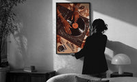 Jeweled Hands on a Record Player print in a slim black frame being hung on a sunlit wall in a monochrome room
