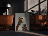 Black-framed Jeweled Hands with Phone and Glass print on the floor in front of a dark wooden console