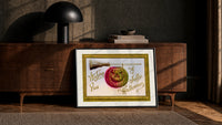 Carved jack-o-lantern hanging on broom print in a black frame leaning against a walnut console in lamplight