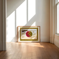 Carved jack-o-lantern hanging on broom print in an oak frame on a sunlit wood floor beneath tall window light