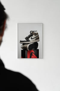 Person viewing a hung Air Jordan 1 Dark Mocha print on a white wall in a gallery-style setting