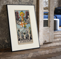 Angel blowing trumpet over rising figures print in a black frame leaning beside a vintage door on parquet