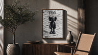 Black and white KAWS graffiti framed poster poster framed above a fluted sideboard beside an olive tree