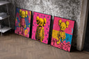 KAWS Companion figures triptych set of three black-framed prints leaning against a raw-plaster wall