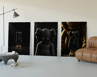 KAWS Companion Matte Black and Gold Set of 3 displayed beside a brown leather sofa