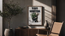 KAWS Companion figure holding monstera plant poster framed above a fluted sideboard beside an olive tree