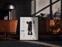 Black-framed KAWS Companion Passing Through figure print on a moody console with designer coffee-table books