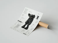 Rolled KAWS Companion Passing Through figure poster beside its crush-resistant kraft shipping tube