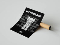 KAWS Companion in white with HYPEBEAST and repeated KAWS text on a black poster shown beside a shipping tube