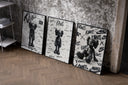 KAWS Companion figure set of three black-framed prints leaning against a raw-plaster wall