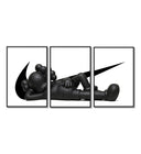Black stylized figure lying down with crossed eyes three-panel set arranged on a gallery wall
