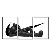 Black stylized figure lying down with crossed eyes three-panel set arranged on a gallery wall