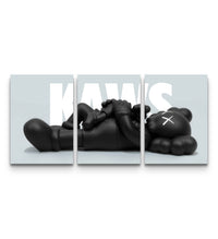 Full three-panel KAWS Companion lounge poster set with a reclining black figure spread across a grey backdrop