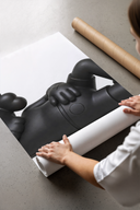 A panel of the Black stylized cartoon character figures in reclined poses set being unrolled on a concrete floor