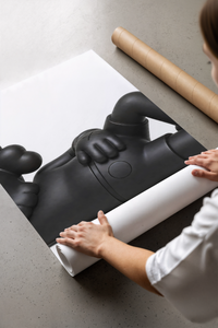 A panel of the Black stylized cartoon character figures in reclined poses set being unrolled on a concrete floor