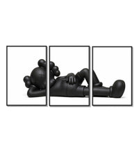 Black stylized cartoon character figures in reclined poses three-panel set arranged on a gallery wall