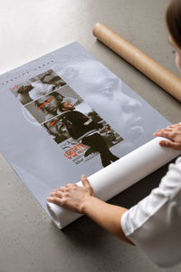 Hands unrolling the Kendrick Lamar DAMN art print on concrete, revealing orange accents and portrait grid