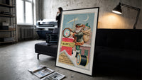 Santa Claus on snowy rooftop print in a slim black frame leaning on a dark sofa in a concrete print studio