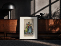Black-framed King of Cups tarot figure print on a moody console with designer coffee-table books