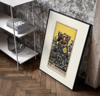 King of Pentacles tarot figure poster in a black frame leaning beside a shelf in a raw-plaster loft