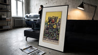 King of Pentacles tarot figure print in a slim black frame leaning on a dark sofa in a concrete print studio