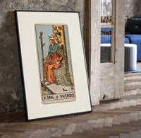 King seated on throne with staff print in a black frame leaning beside a vintage door on parquet