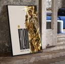 Man in gold striped suit pointing up print in a black frame leaning beside a vintage door on parquet