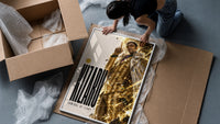Man in gold striped suit pointing up framed print being unpacked from protective bubble wrap and a box