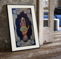 Upraised hand with alchemical symbols print in a black frame leaning beside a vintage door on parquet
