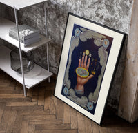 Upraised hand with alchemical symbols poster in a black frame leaning beside a shelf in a raw-plaster loft