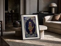 Upraised hand with alchemical symbols print in a black frame leaning on a travertine table in a sunlit lounge